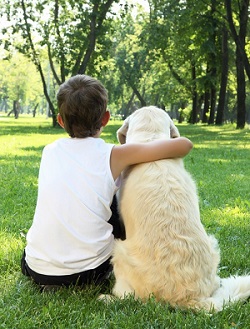 boy with arm around dog